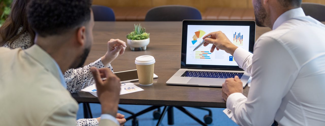 Financial advisor or lawyer with couple explaining options. They are discussing finance charts and graphs on a laptop computer. They sitting in an office and are discussing something with the agent